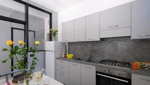 Eine moderne Küche mit grauen Schränken, einem Edelstahlherd und einer grauen Spritzschutzwand.
