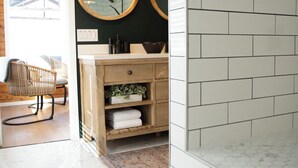 Een badkamer met witte tegels, houten kastjes en een spiegel met houten lijst.