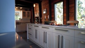 Een moderne keuken met witte kasten, een groot eiland en uitzicht op de omgeving door een raam.