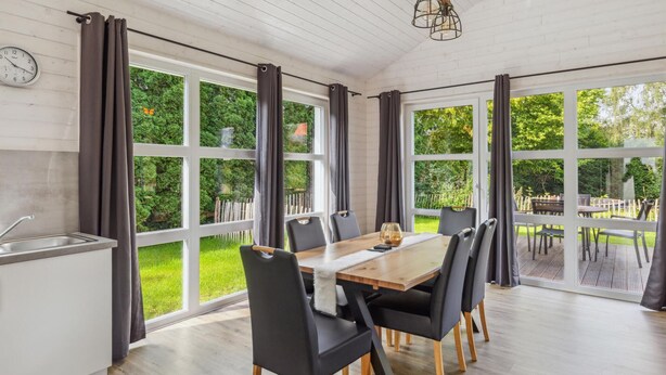 Une cuisine moderne avec un coin repas, de grandes fenêtres et une vue sur le jardin.