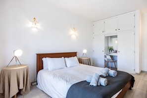 A hotel room with a bed, bedside tables, a wardrobe, and a chair.
