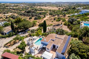 A residential property with a swimming pool, solar panels, and a view of the surrounding countryside.
