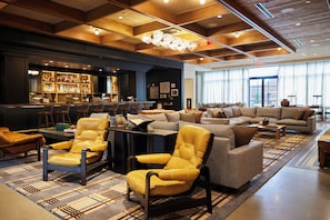A spacious lobby with a bar area, leather armchairs, a sofa set, and a patterned rug.