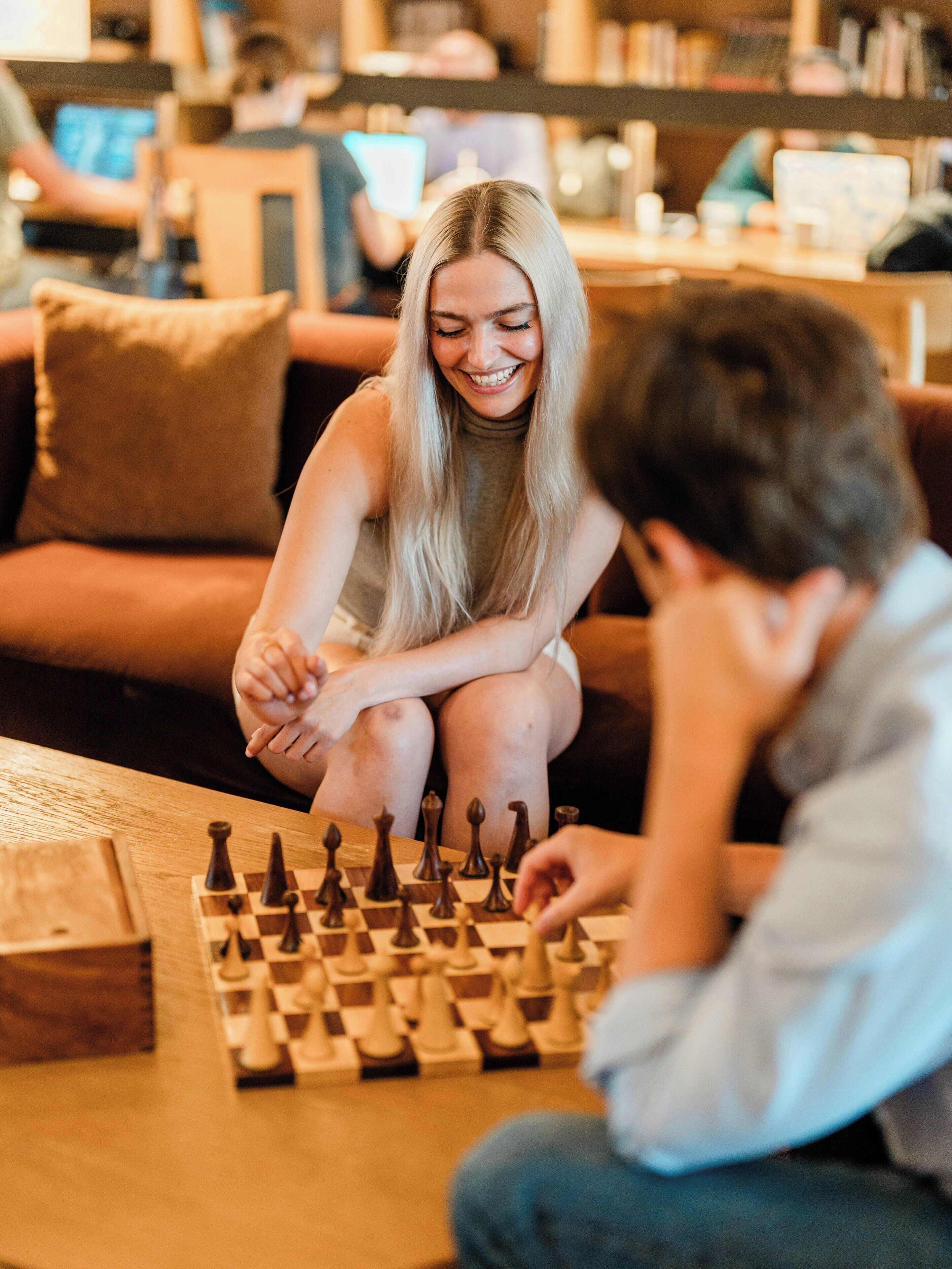 Two people playing chess on a wooden table in a cozy indoor setting.