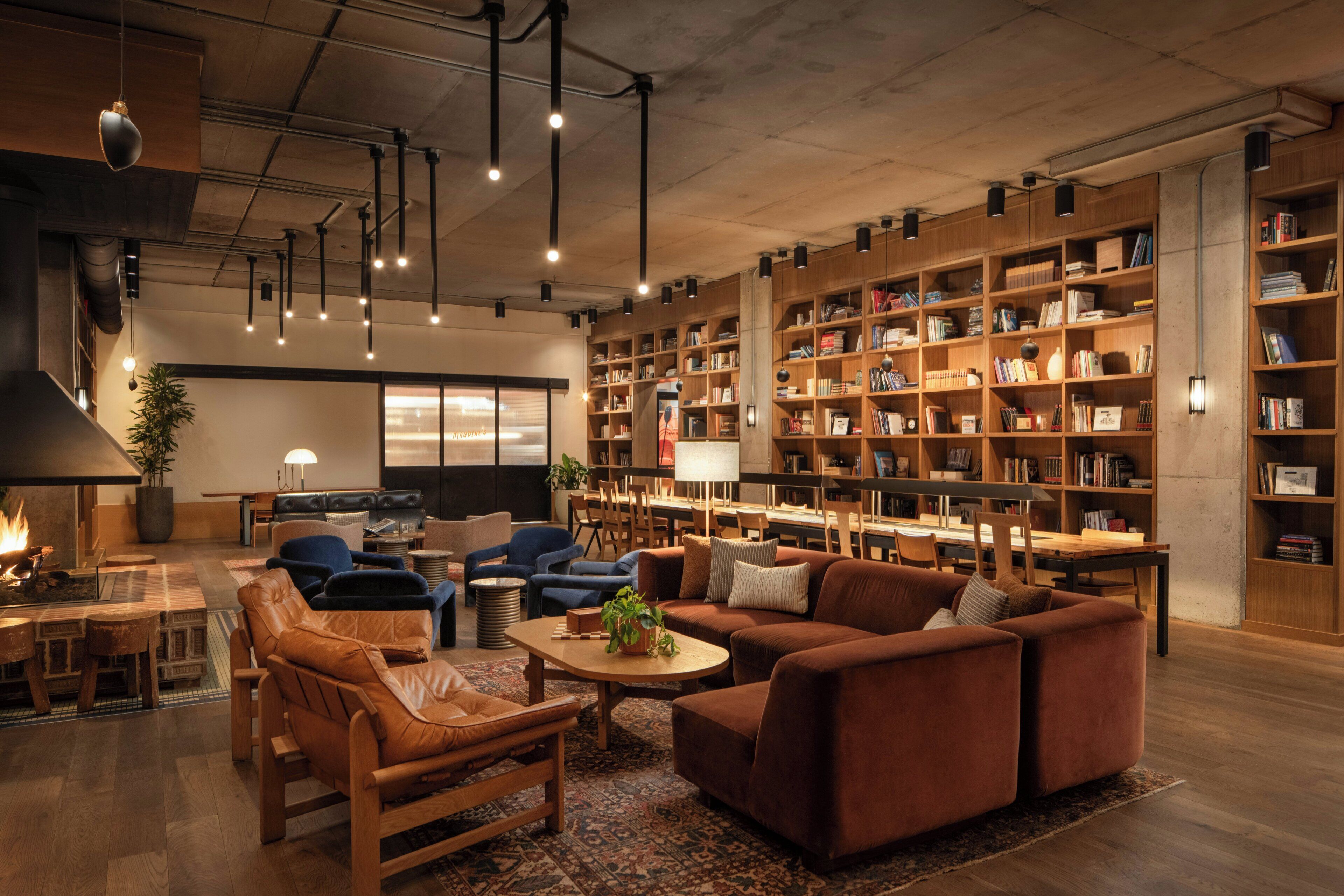 A spacious living area with a fireplace, leather sofas, a dining table, and a large bookshelf filled with books.