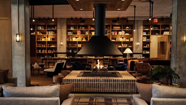 Un rincón acogedor con chimenea, asientos cómodos y una amplia estantería llena de libros.