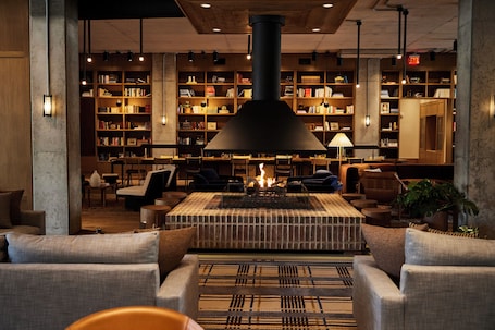 A cozy lounge area with a fireplace, comfortable seating, and a large bookshelf filled with books.