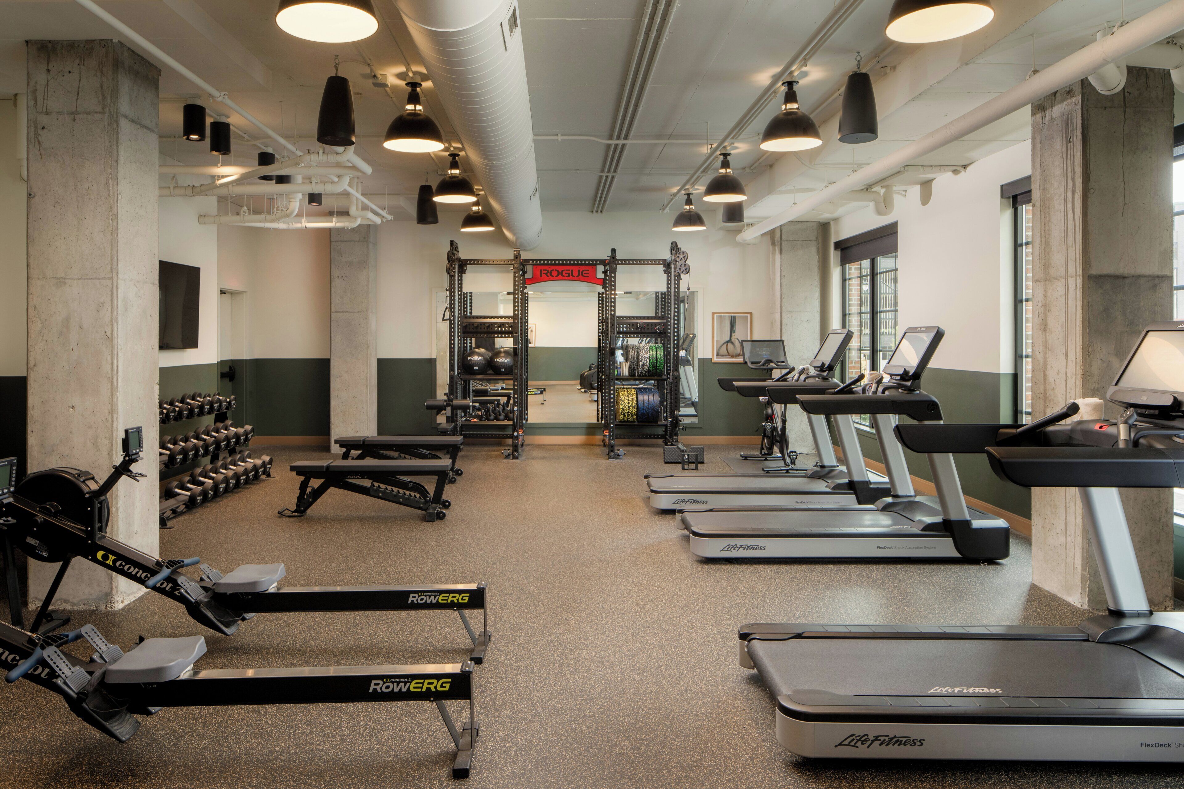 A gym with treadmills, weight machines, and dumbbells.