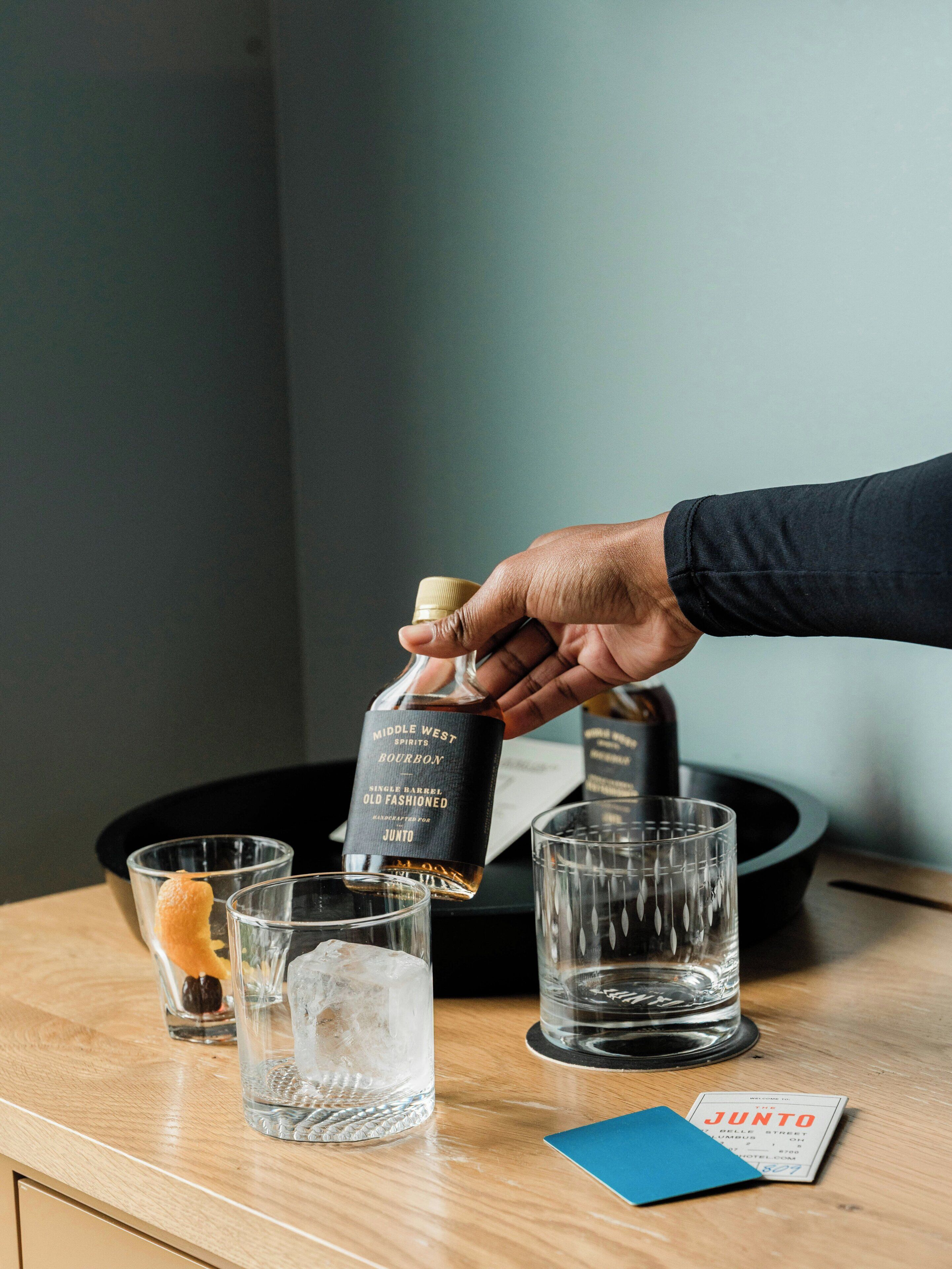 A hand pouring bourbon into a glass with ice.