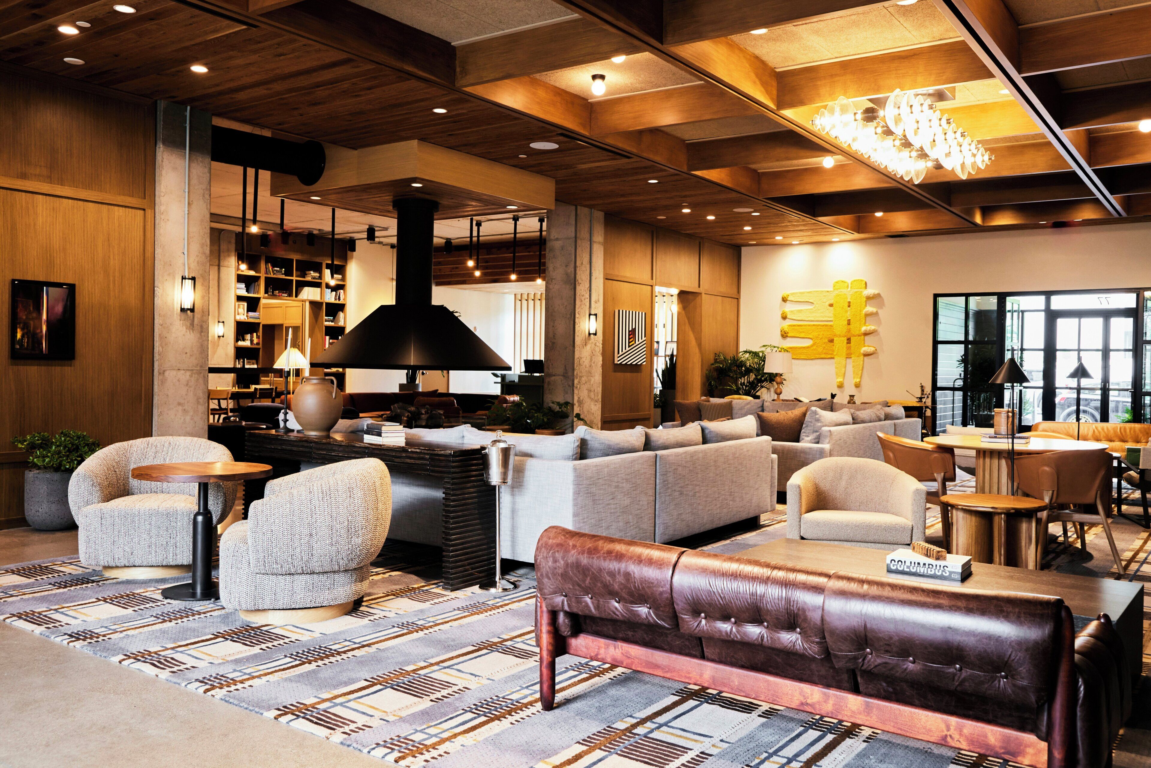 Eine moderne Lobby mit einer Couch, Sesseln, einer Bank, einem Couchtisch, einem Bücherregal und einer Chandelier.