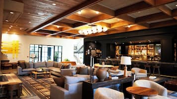 Un moderno espacio de salón con sofás, una mesa de centro y un bar con estantes llenos de botellas.