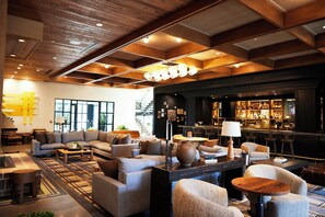 A modern lounge area with sofas, a coffee table, and a bar with shelves of bottles.