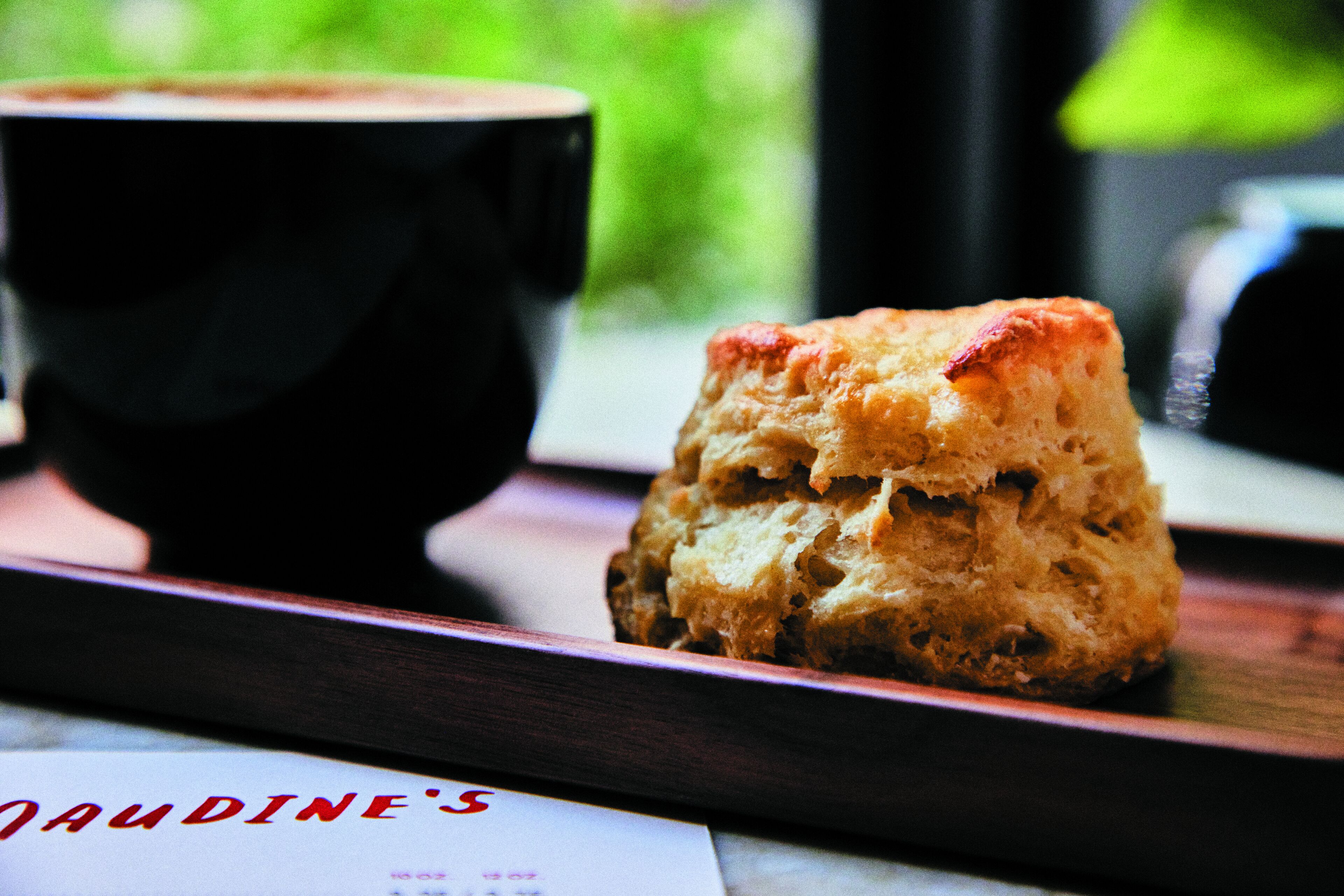 A tray with a scone and a cup of coffee, with a menu visible in the foreground.