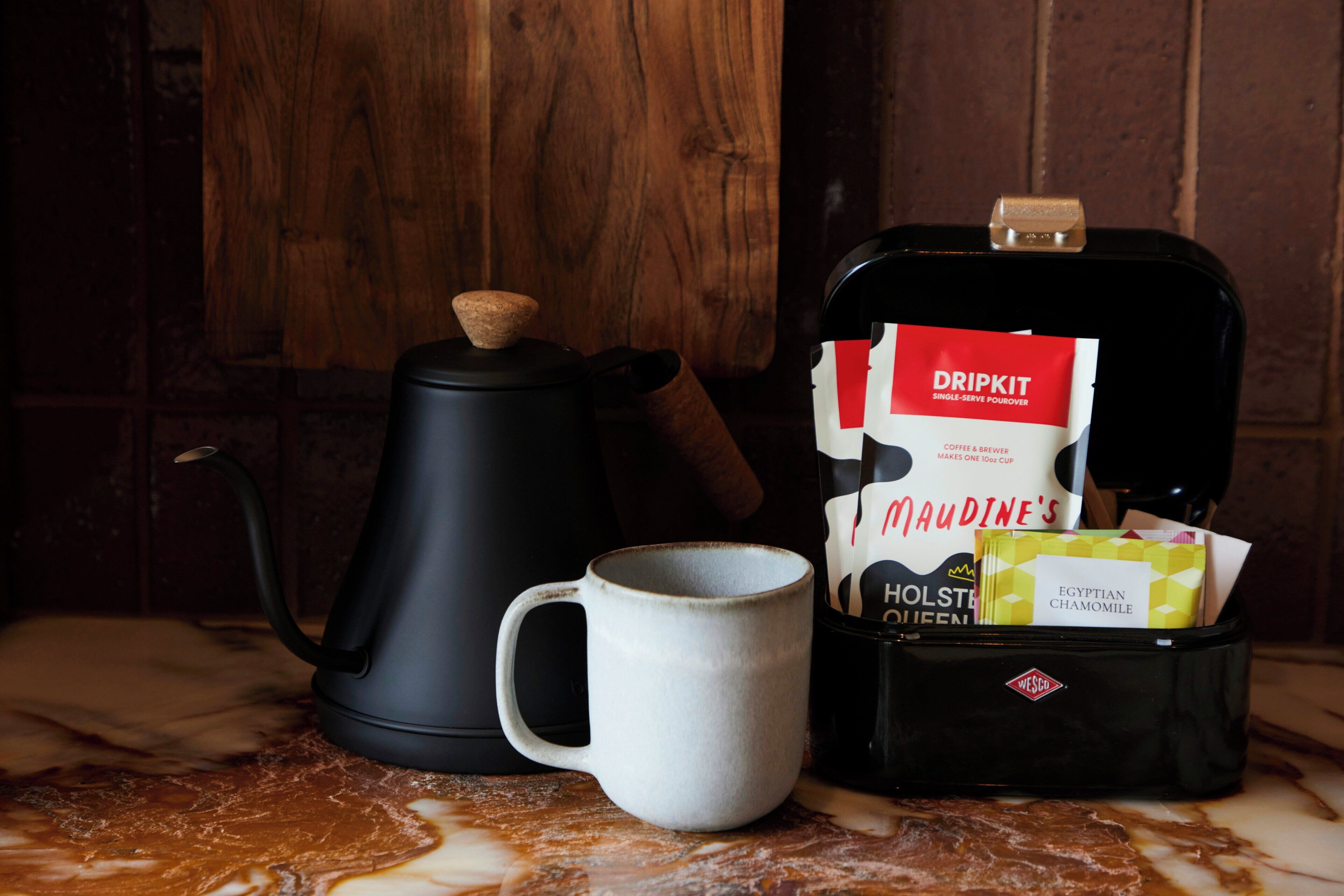 A coffee maker, a mug, and a coffee bag on a marble surface.