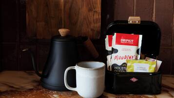 A coffee maker, a mug, and a coffee bag on a marble surface.