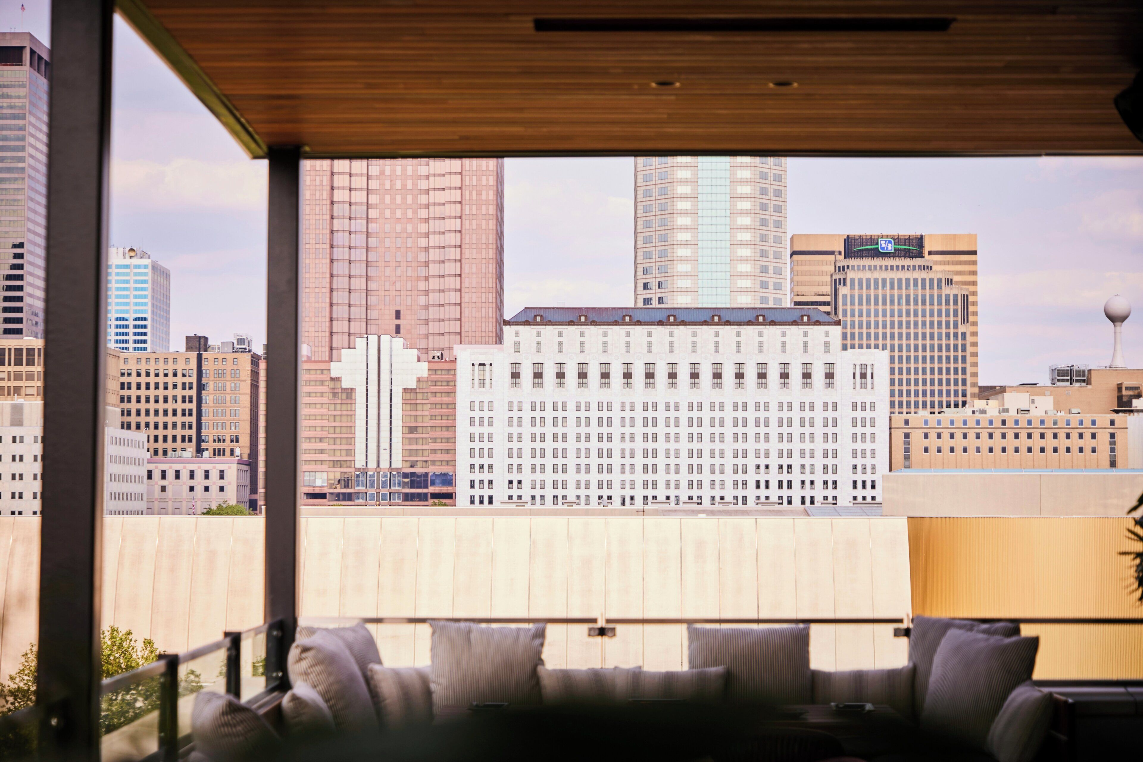Una habitación con vista a un paisaje urbano, que presenta un edificio grande con una estructura cruciforme distintiva.