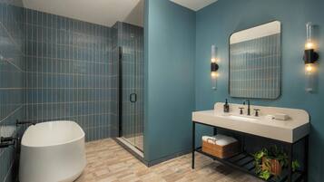A modern bathroom with a large bathtub, a glass shower enclosure, and a vanity with a mirror and lighting.