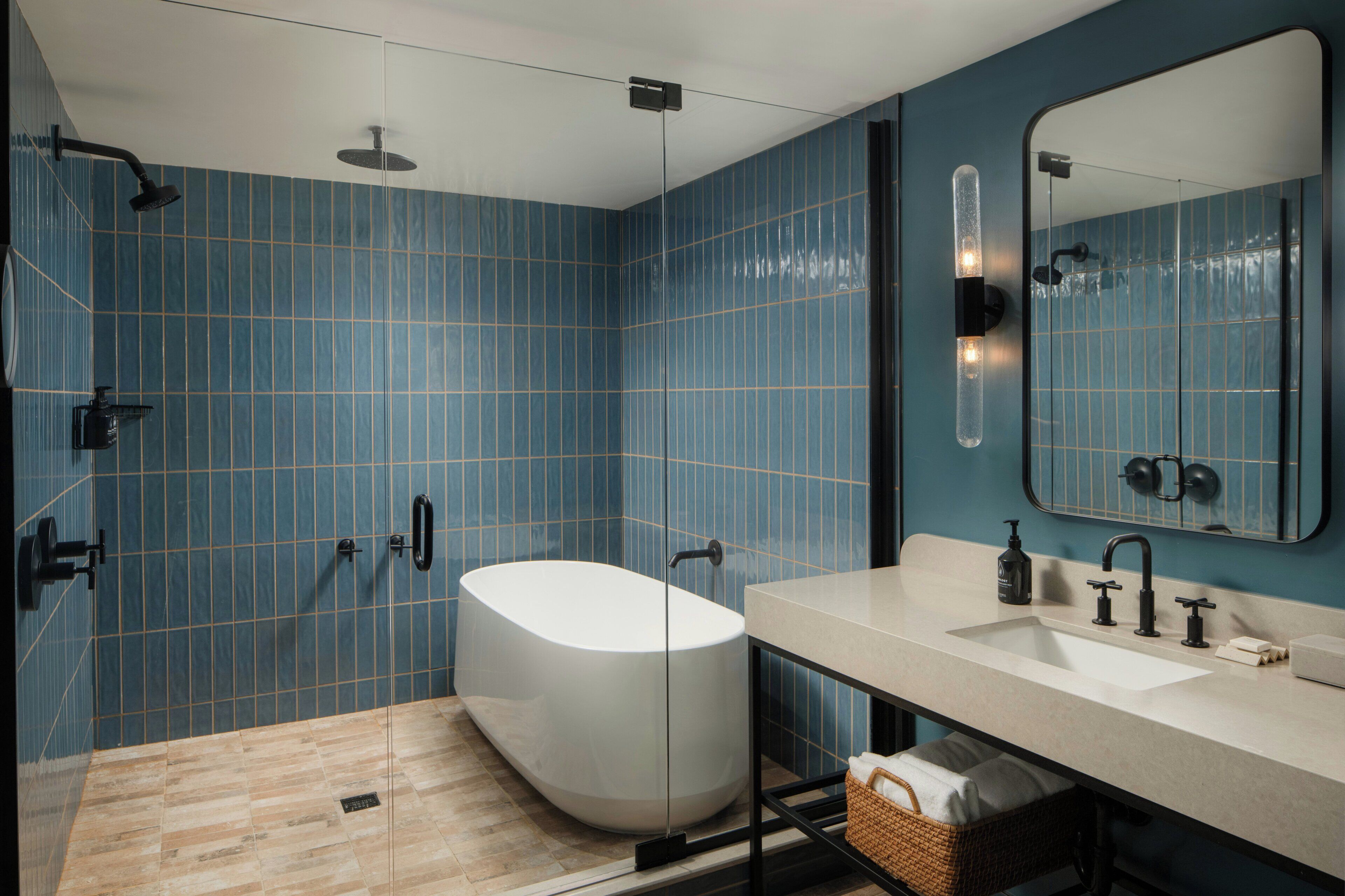 A modern bathroom with a freestanding bathtub, a large mirror, and a vanity with a sink.