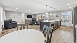 Una cocina moderna con una isla central, sofás grises y un comedor.