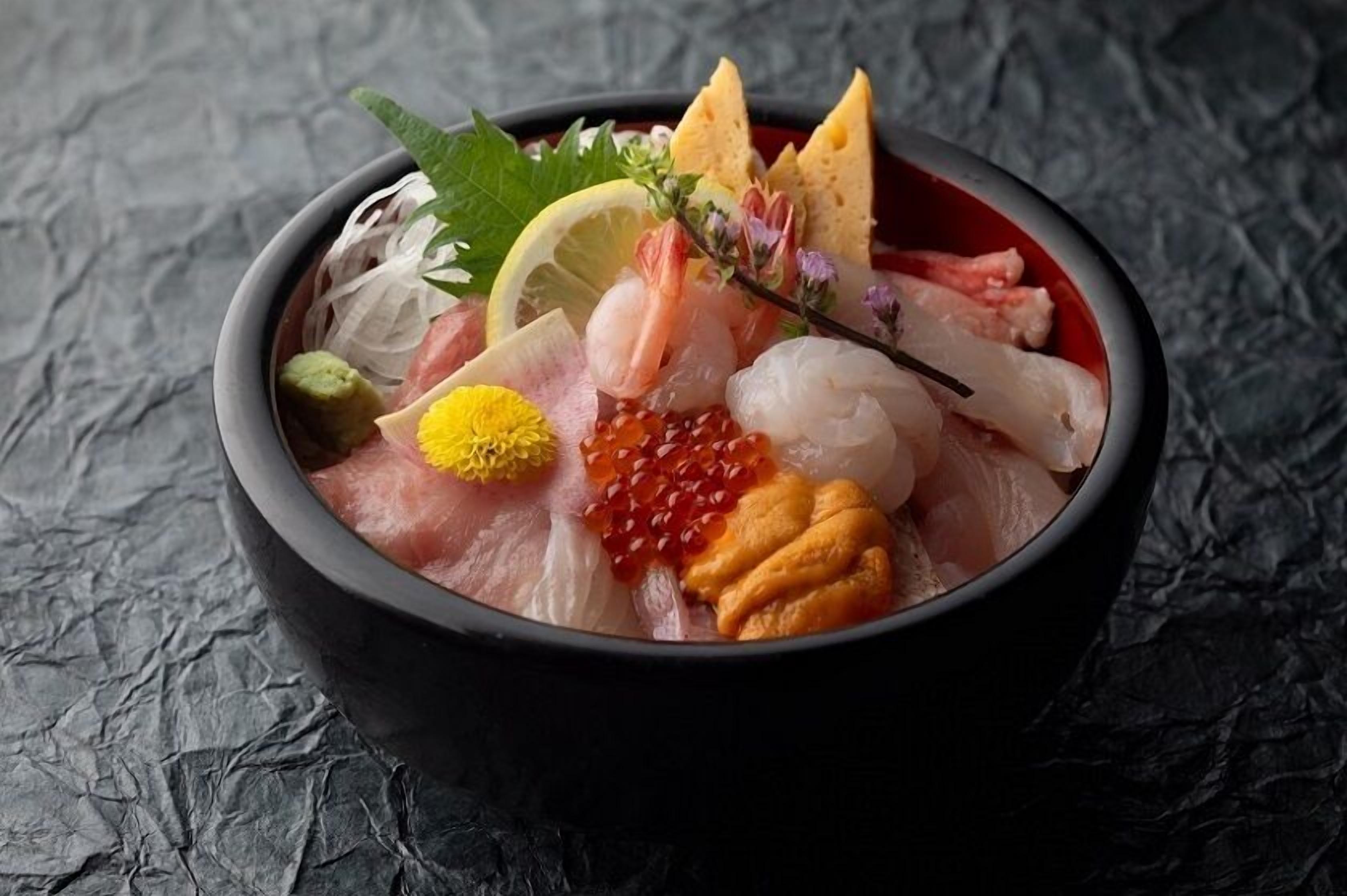 A bowl of sashimi with various toppings and garnishes.