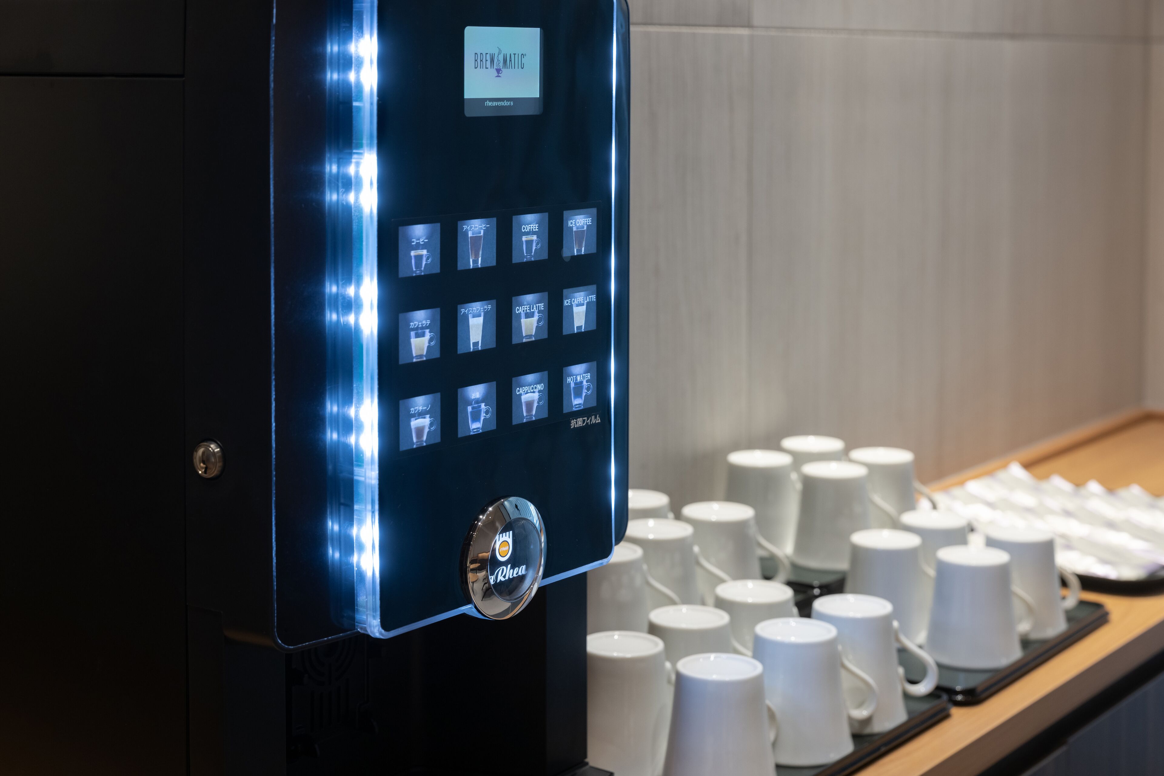 Une machine à café dotée d’une interface numérique et d’un assortiment de tasses blanches présentées sur un plateau.