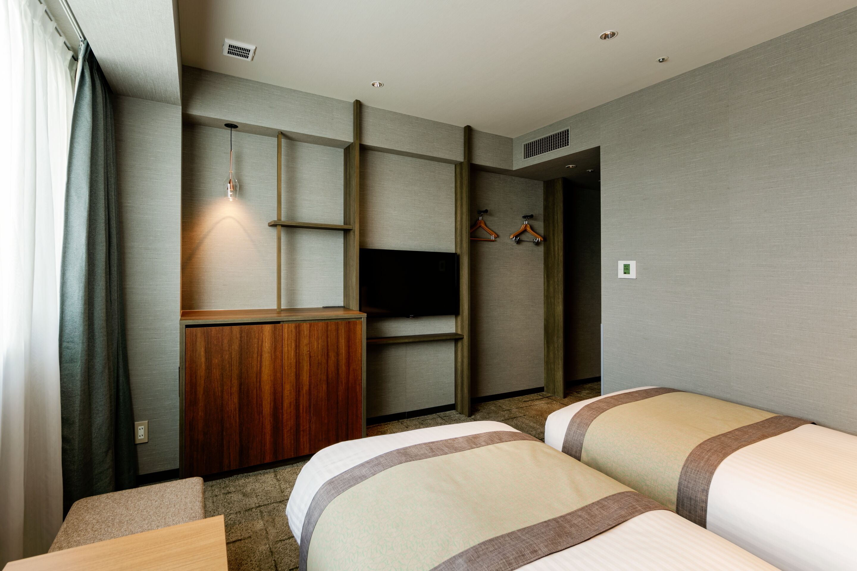 A hotel room with a bed, a desk, a television, and a wardrobe.