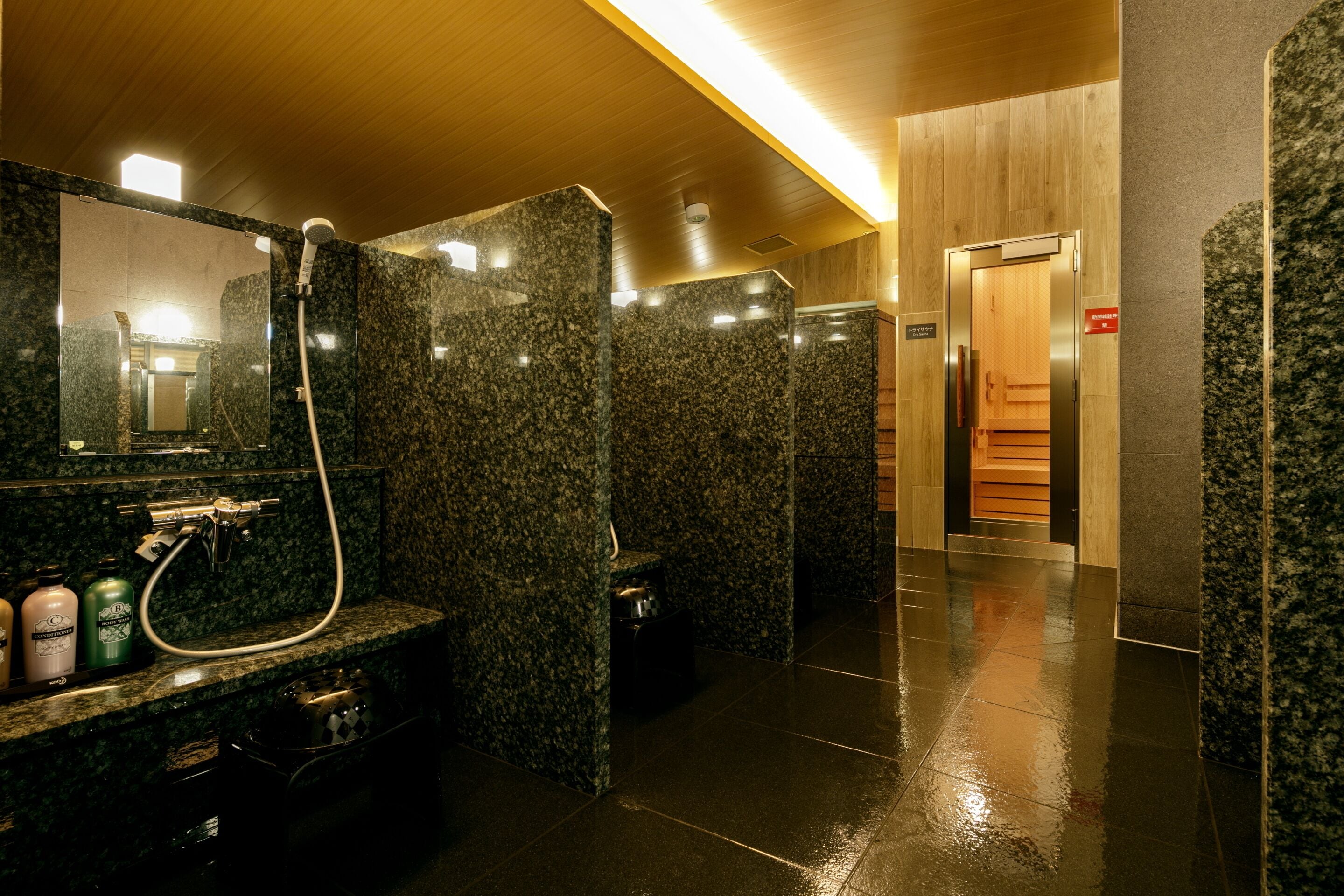 A modern bathroom with granite countertops, a mirror, a shower, and a wooden panel wall.