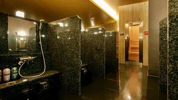 A modern bathroom with granite countertops, a mirror, a shower, and a wooden panel wall.