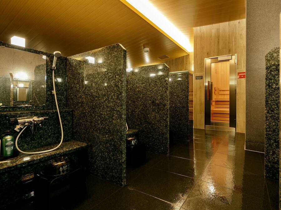 A modern bathroom with granite countertops, a mirror, a shower, and a wooden panel wall.