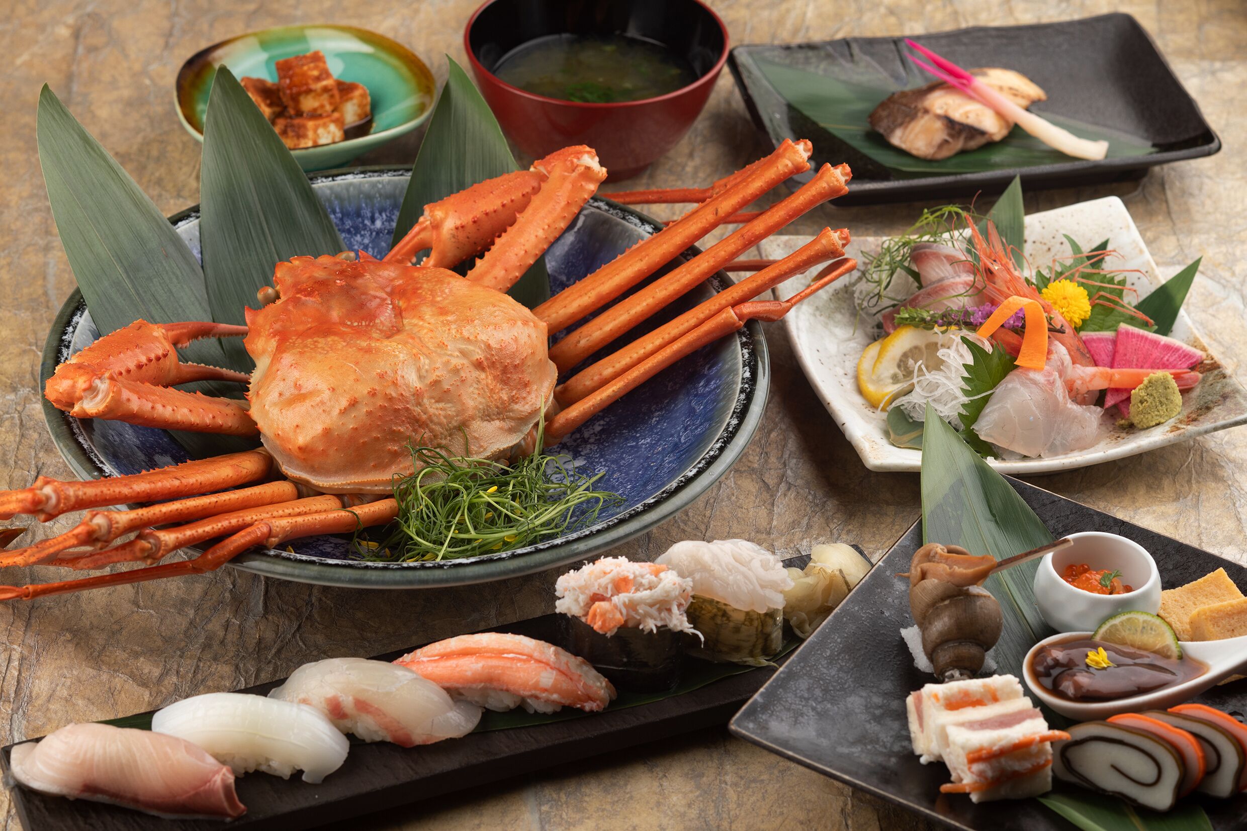 A variety of seafood dishes including crab legs, sashimi, and sushi on a table.