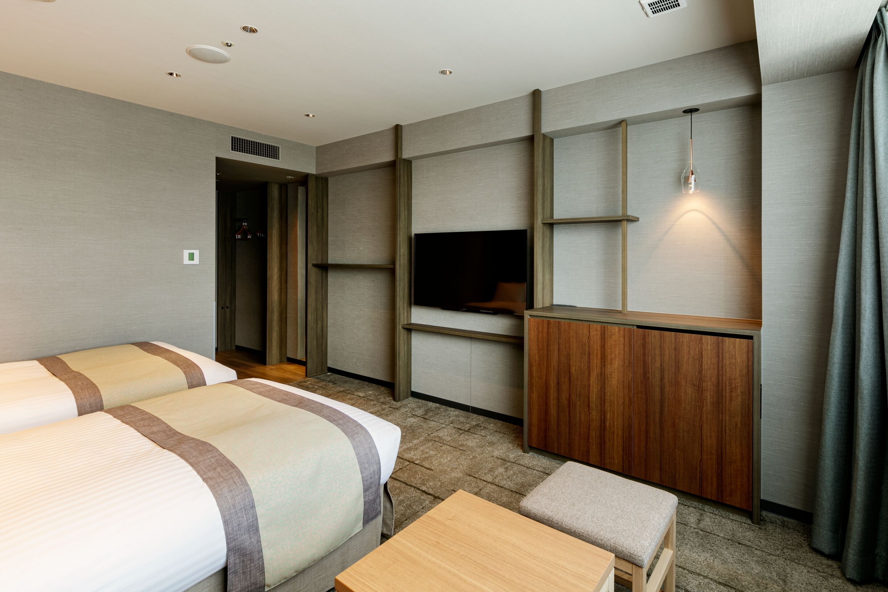 Una habitación de hotel con dos camas, televisión, un armario de madera y una mesita.