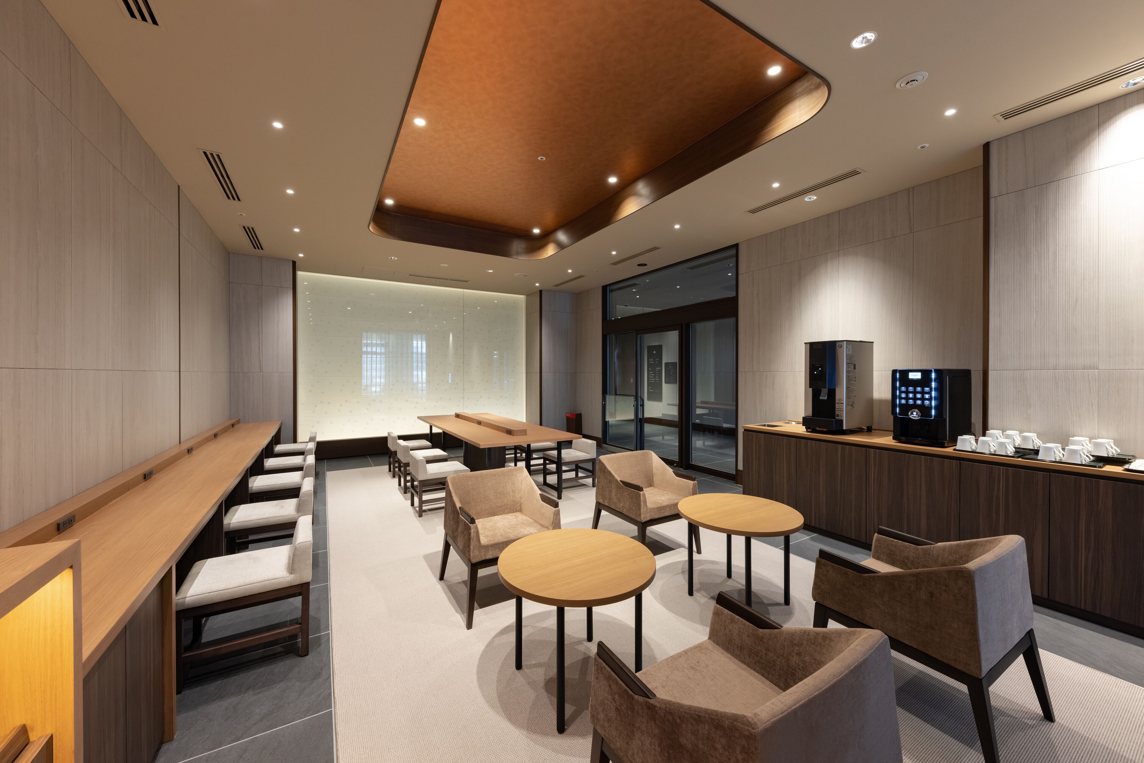 Une salle de conférence moderne, dotée d’une longue table, de plusieurs chaises, d’un coin café et d’une grande fenêtre offrant une vue sur la ville.