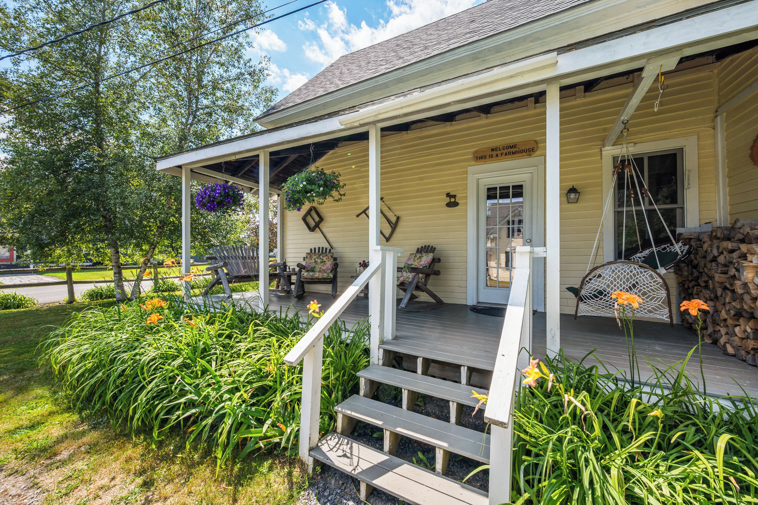A farmhouse with a porch, outdoor seating, and a welcome sign.