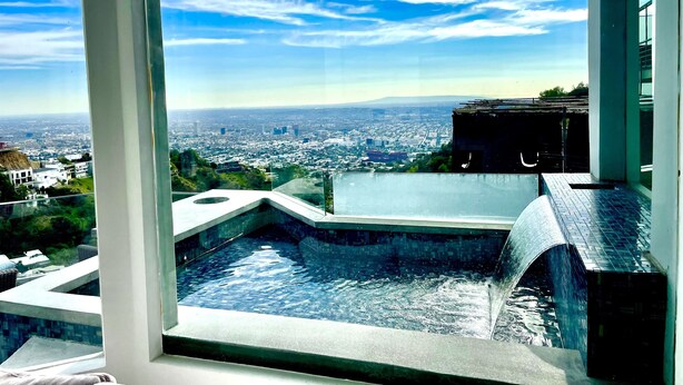 A modern hotel room with a large window overlooking a cityscape and a small indoor water feature. - Hollywood hills Sanctuary, Views from Santa Monica to downtown LA. (Los Angeles)