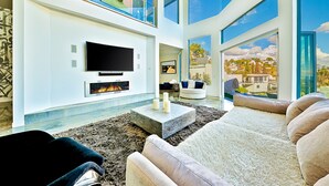 A modern living room with a fireplace, large windows, and a flat-screen TV. - Hollywood hills Sanctuary, Views from Santa Monica to downtown LA. (Los Angeles)