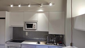 Een moderne keuken met witte kasten, een ingebouwde magnetron, een gasfornuis en een spoelbak.