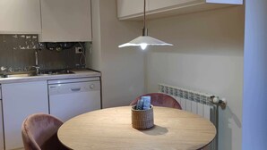 Een moderne keuken met witte kasten, een ronde houten tafel en twee paarse stoelen.