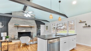 Una cocina moderna con una isla central, una chimenea de piedra y vistas al exterior.