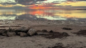 Una playa con mar tranquilo y un atardecer.