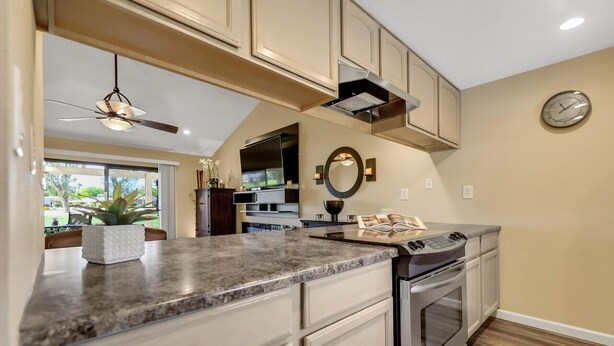A kitchen with a granite countertop, stainless steel appliances, and beige cabinetry. - Desert Paradise Retreat Awaits on Golf Course with Sunset & Mountain Views (Palm Desert)
