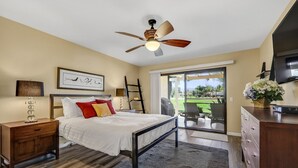 A bedroom with a bed, nightstand, dresser, ceiling fan, and a view of the outdoors. - Desert Paradise Retreat Awaits on Golf Course with Sunset & Mountain Views (Palm Desert)