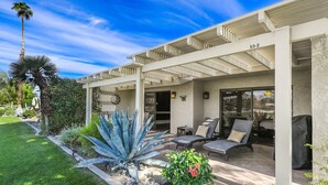 A covered patio with outdoor seating, a well-maintained garden with agave plants, and a clear blue sky. - Desert Paradise Retreat Awaits on Golf Course with Sunset & Mountain Views (Palm Desert)