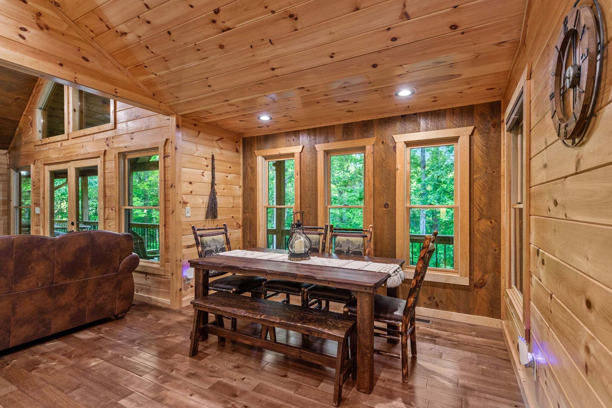 L'intérieur d'un chalet en bois, avec une table à manger, des bancs et un canapé.