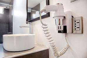 A modern bathroom with a white sink and a wall-mounted telephone. - MAGIC PACKER HOSTEL (Cusco)