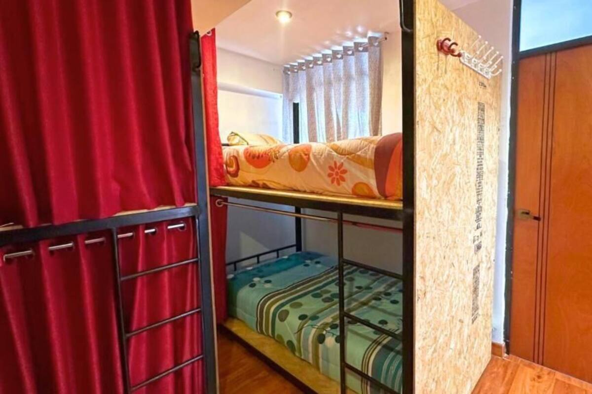 Un dormitorio con literas, una puerta de madera y una cortina.