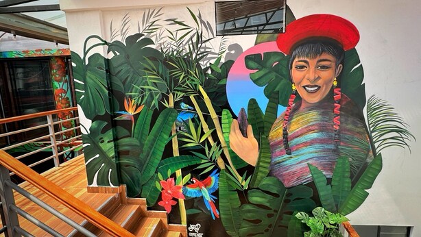 Un escalier orné d’une fresque représentant des plantes tropicales et une personne.