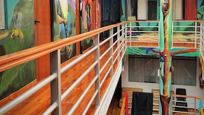 Un intérieur à plusieurs niveaux, agrémenté de peintures murales colorées, d’un plancher en bois et d’un plafond en verre.