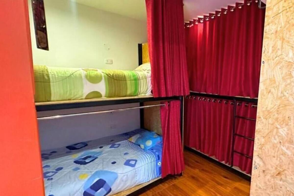 Un dormitorio con literas, cortinas rojas y una pared de madera.