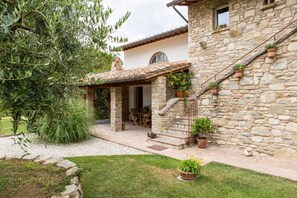 A stone house with a patio, outdoor seating, and potted plants. - Villa Mignola by MMega (Perugia)