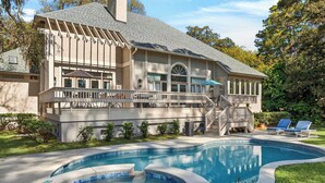 Uma casa com piscina, um deck coberto e uma escadaria que leva a uma varanda.